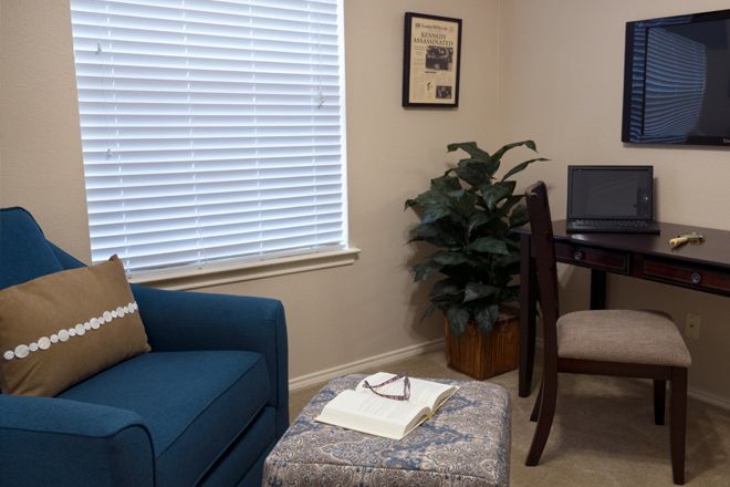 A cozy living room with a blue sofa, desk, and plant by the window.
