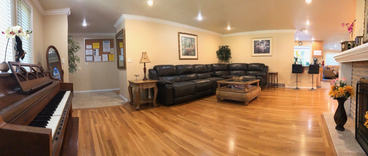 A cozy living room with hardwood flooring, featuring a large sectional sofa, a coffee table, and warm lighting.