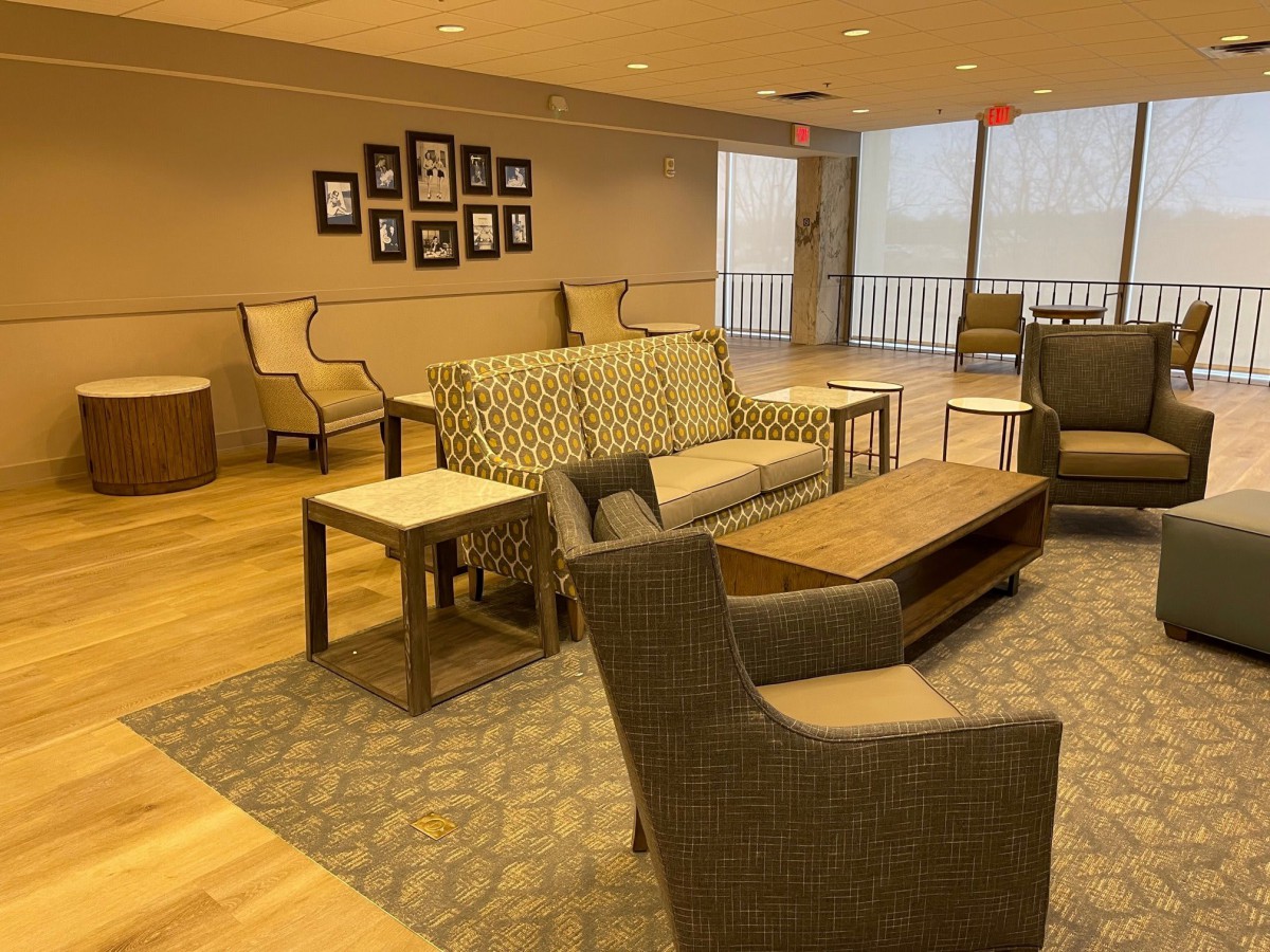 A cozy lounge area featuring various seating options with sofas, chairs, and tables, accented by wall art and a carpeted floor.