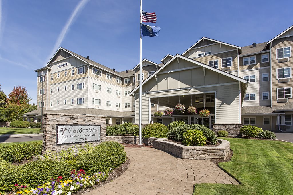 A well-maintained hotel entrance with a landscaped path and flags flying.
