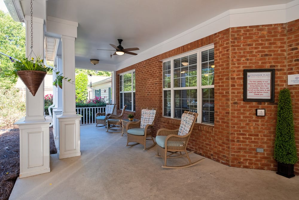 A cozy patio with brick walls, seating arrangements, and a ceiling fan.