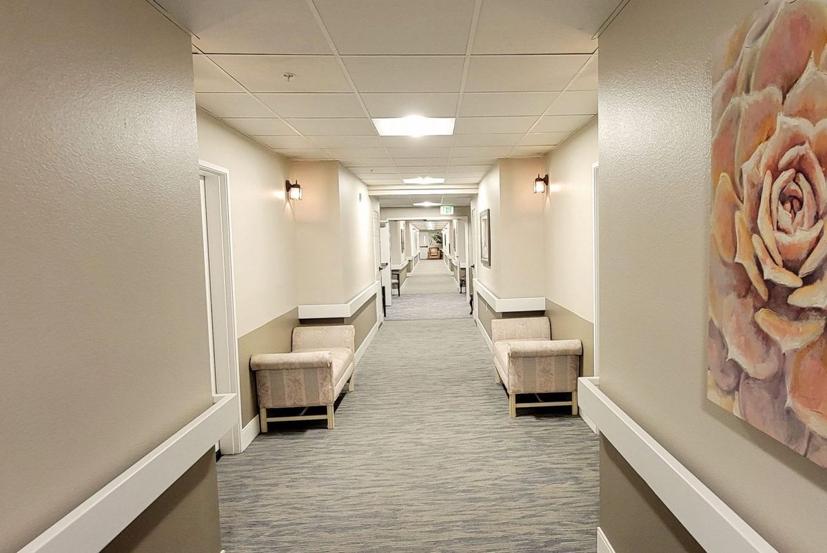 An empty hospital corridor with benches along the walls.