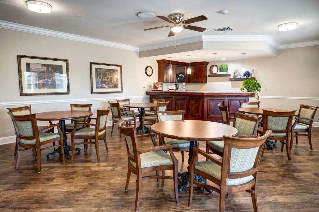 A cozy dining area with wooden tables and chairs, featuring a ceiling fan and elegant decor.