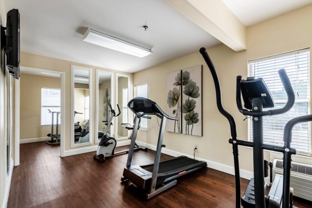 A home gym with various exercise equipment including a treadmill and elliptical machine.