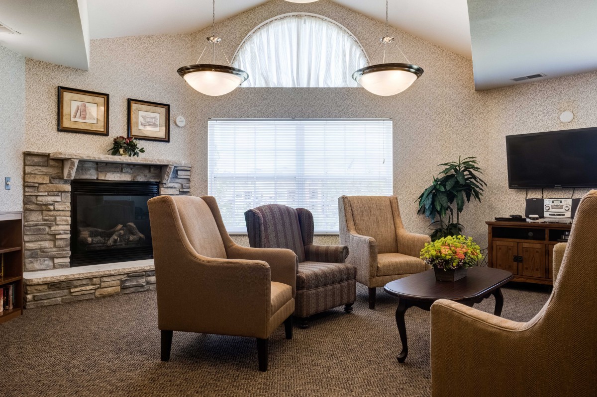 A cozy living room featuring comfortable seating, a fireplace, and natural light from a large window.