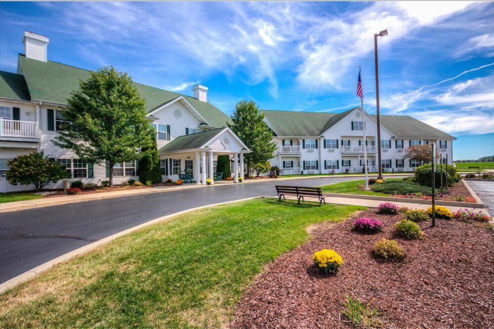 A view of a large building surrounded by well-maintained landscaping under a blue sky with clouds.