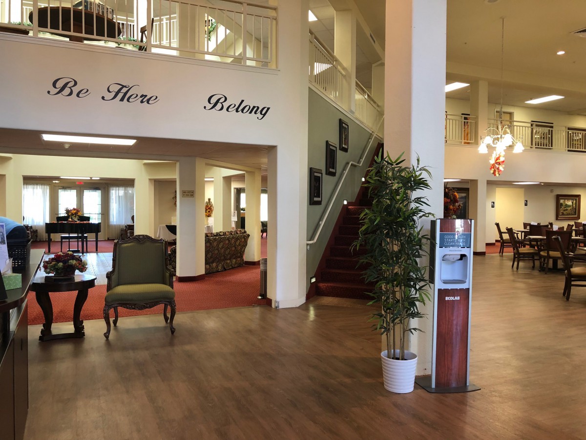 A spacious lobby with elegant furniture, potted plants, and a staircase leading to an upper level.