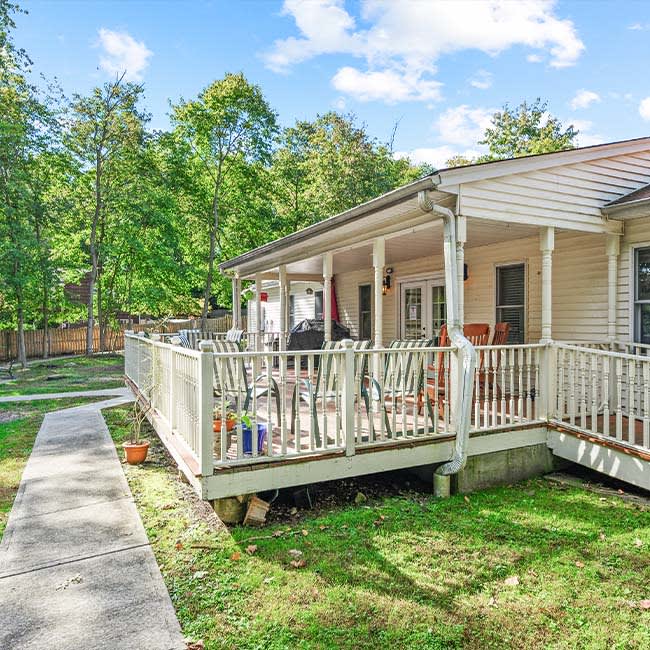 A cozy house with a spacious deck overlooking a lush backyard.