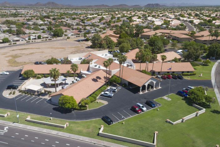 Aerial view of a suburban community with buildings, a parking lot, and surrounding landscape.