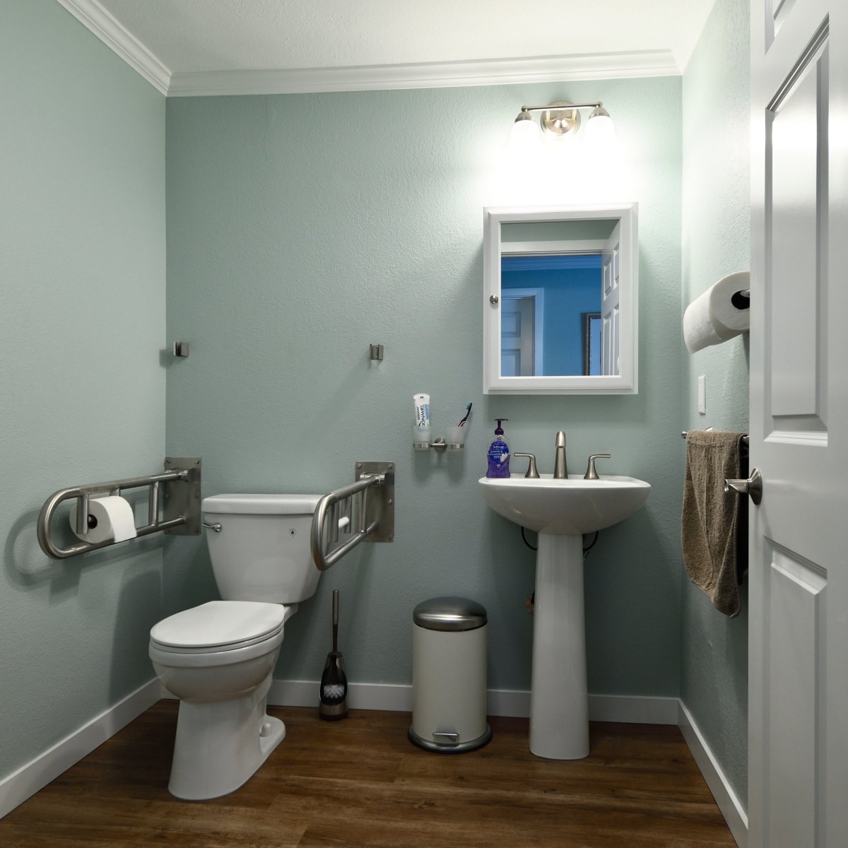 A well-organized bathroom with accessibility features, including grab bars near the toilet and sink.