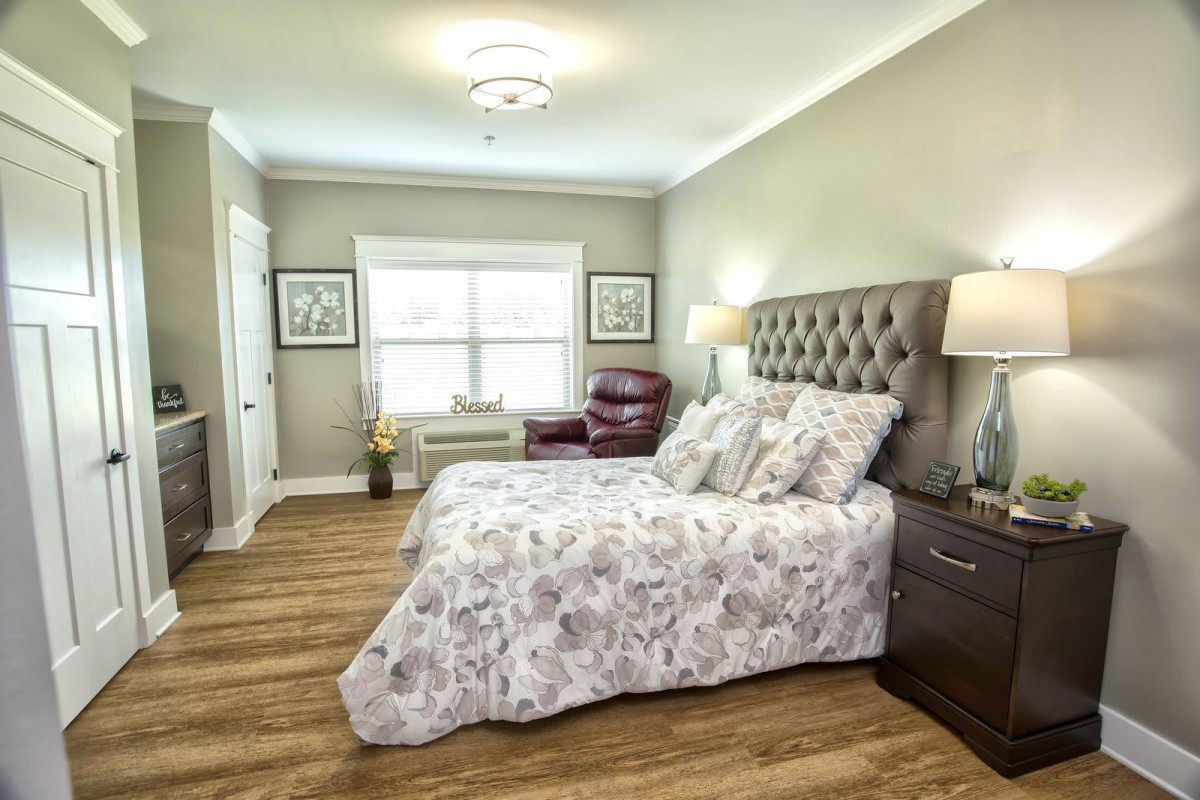 A cozy bedroom with a floral-patterned bedspread, tufted headboard, and elegant decor.