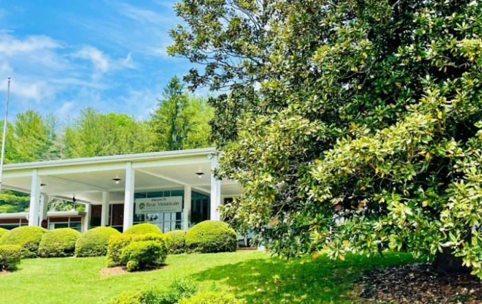 A beautiful building surrounded by lush greenery and trees under a clear blue sky.