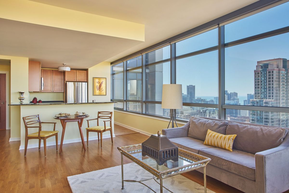 A modern apartment living room with large windows offering a stunning city view.