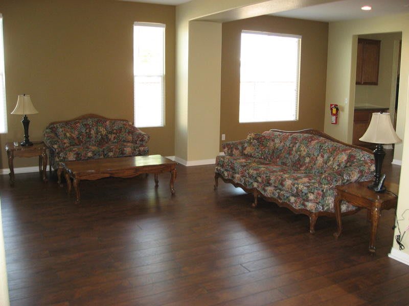 A living room with a hardwood floor, featuring patterned sofas and a wooden coffee table.