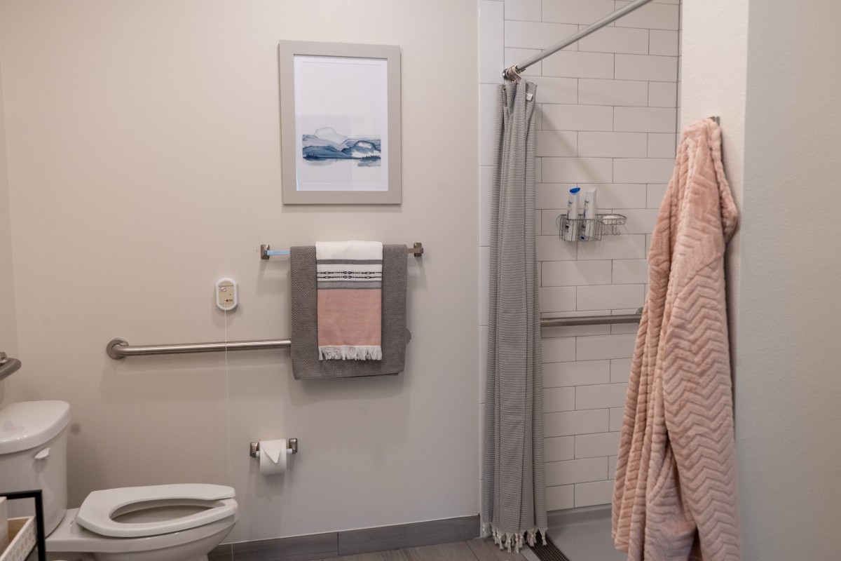 A tidy bathroom with a shower, towels, and framed wall art.