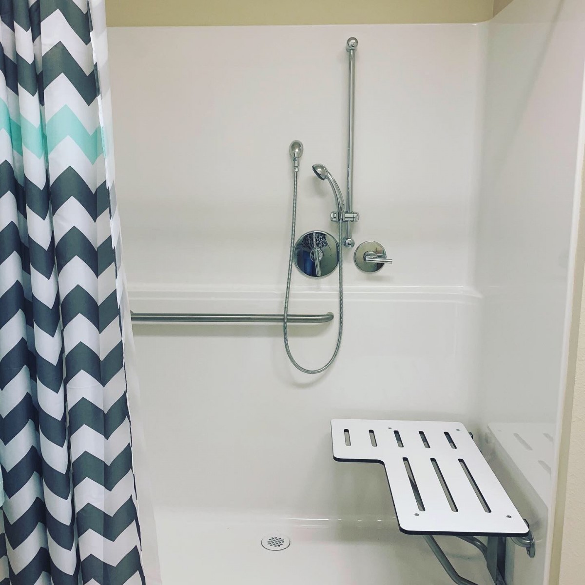 Accessible shower with a seat and grab bar.