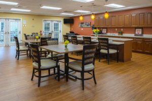 A modern dining area with tables and chairs, featuring wood flooring and warm lighting.