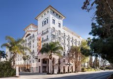 A view of a large hotel building with palm trees in an urban setting.
