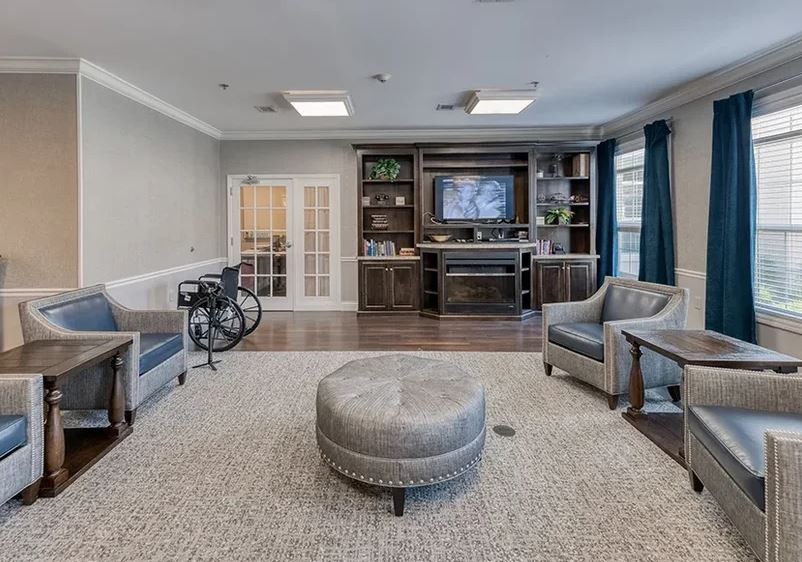 A cozy living room with a television, bookshelves, seating area, and a bicycle.