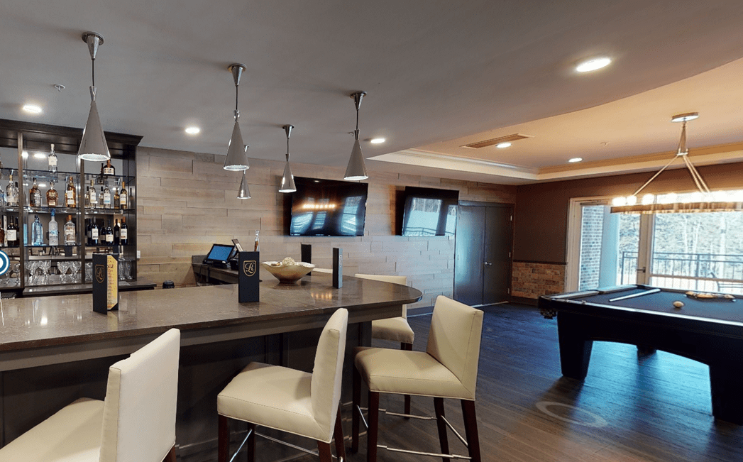 A modern and stylish open living area with a kitchen island, bar stools, and a pool table.