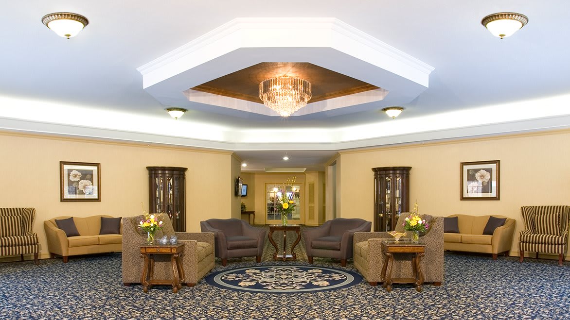 A well-furnished lobby featuring comfortable seating and a central chandelier.