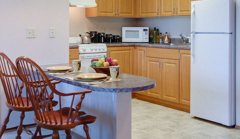 A cozy kitchen with wooden cabinets and a countertop adorned with a fruit basket.
