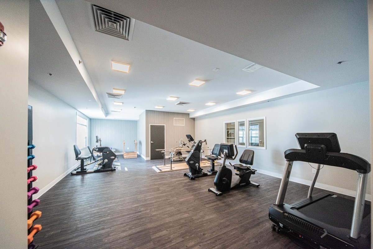 An empty gym with modern exercise equipment, including treadmills and stationary bikes.