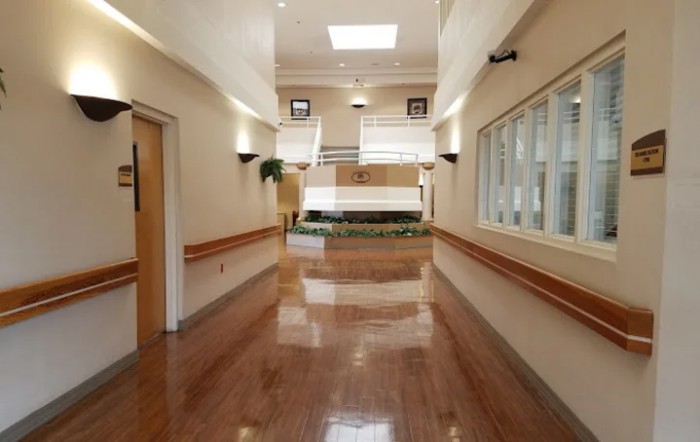 A clean and modern hallway in a building, featuring large windows and bright lighting.