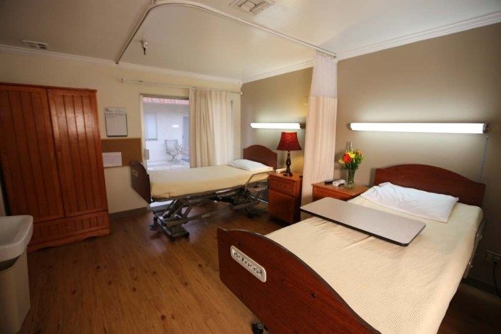 A hospital room with two patient beds, each equipped with medical facilities and separated by curtains.