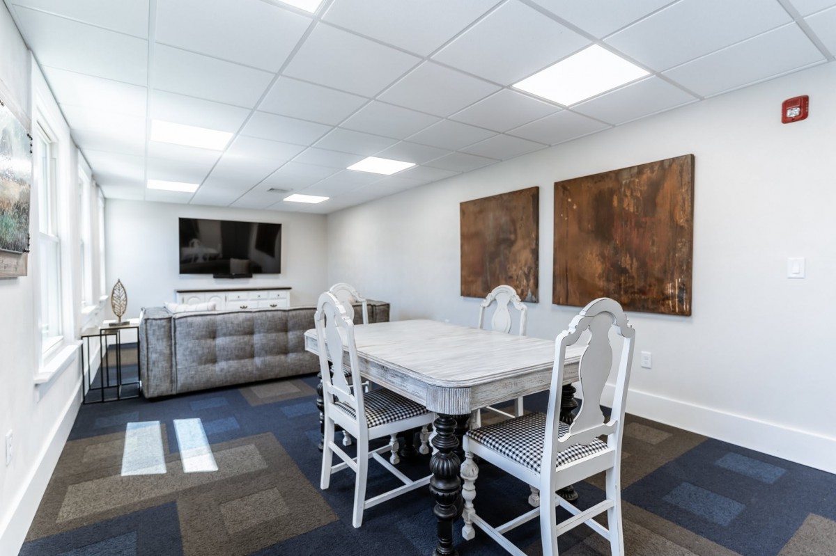 A modern conference room with a white table, matching chairs, and abstract artwork on the walls.