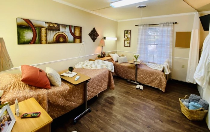 A cozy shared bedroom with two single beds, stylish decor, and a large window allowing natural light.