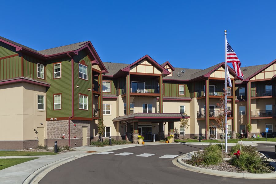A sunny day view of a residential senior living facility with landscaped surroundings.