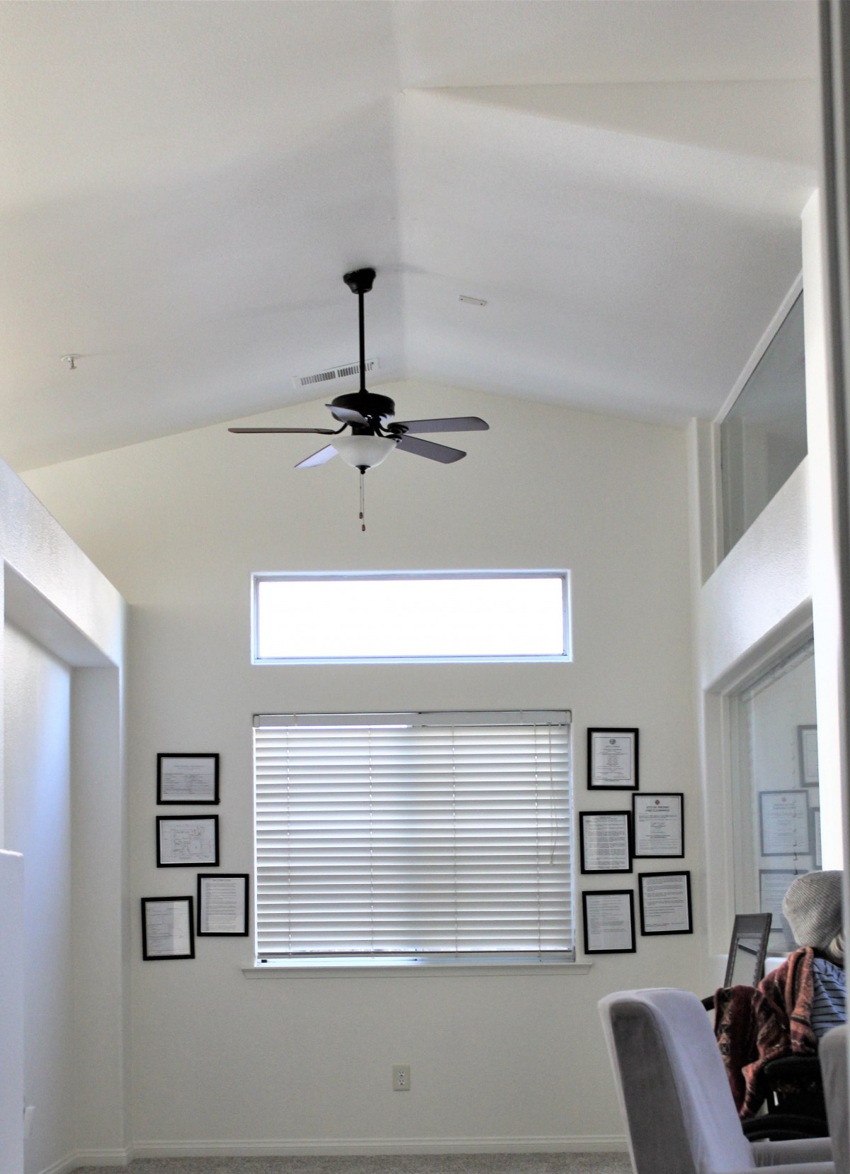 A modern living room with a ceiling fan and framed wall decorations.