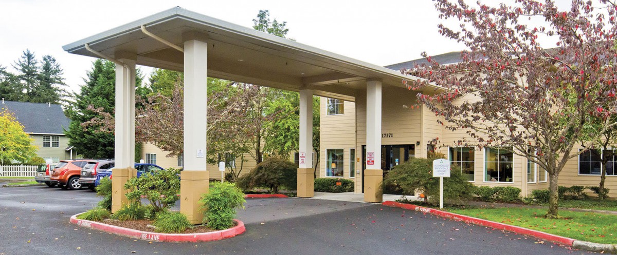 Entrance of a hotel with a covered driveway and columns.