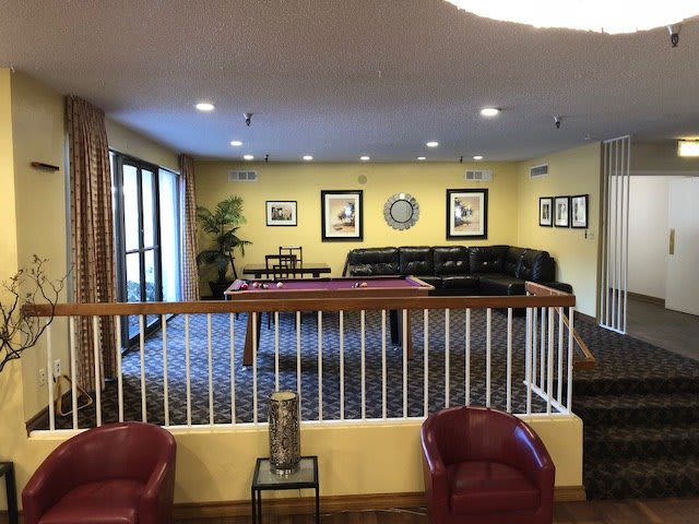 A cozy living room featuring a pool table, comfortable sofas, and artwork on the walls.