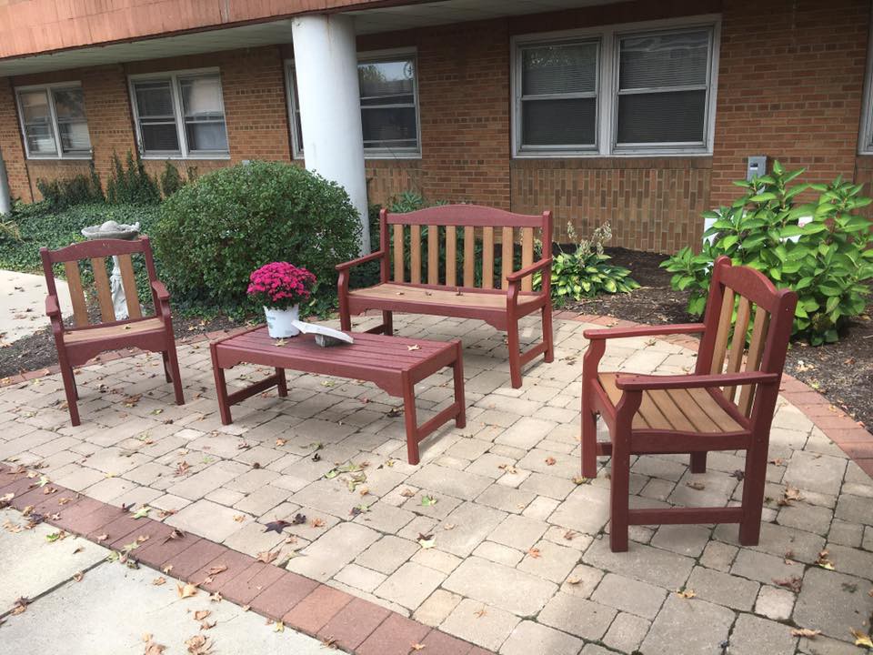A cozy brick patio with wooden benches, a table, and a potted plant.