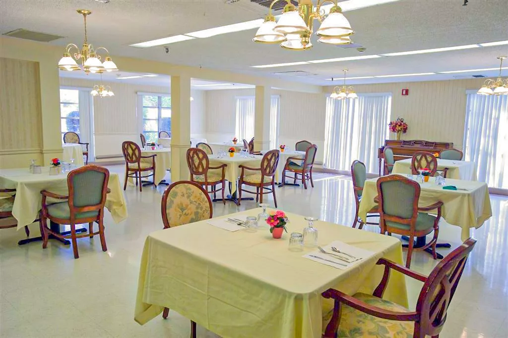 An elegant dining room with neatly arranged tables and chairs, featuring soft lighting and a warm ambiance.