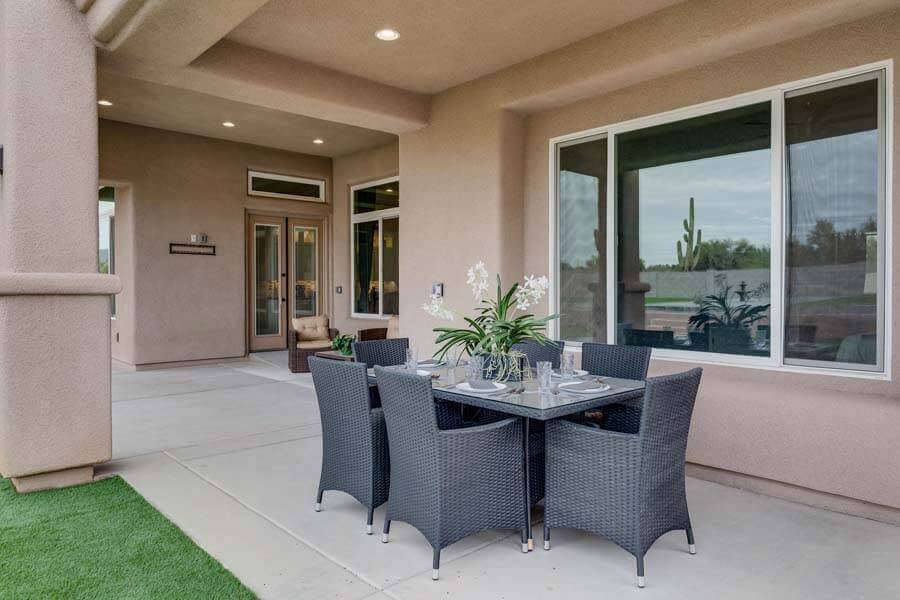 A modern outdoor patio with a dining set and comfortable seating under a covered area.