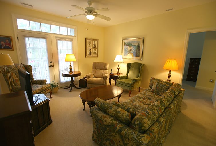 A cozy living room with elegant furnishings, including a sofa, armchairs, and warm lighting.