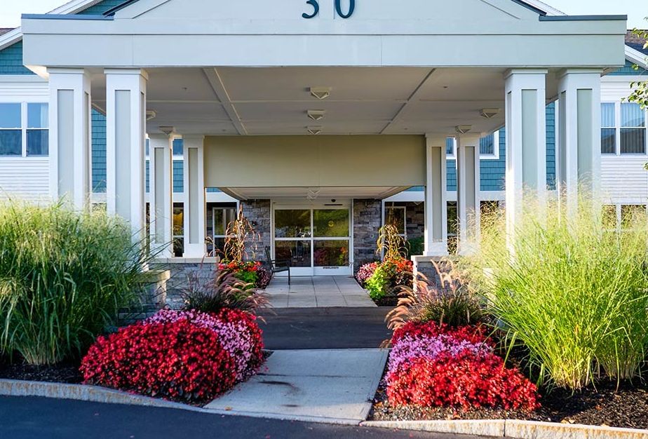 A beautifully landscaped entrance to a building with vibrant flowers lining the pathway.