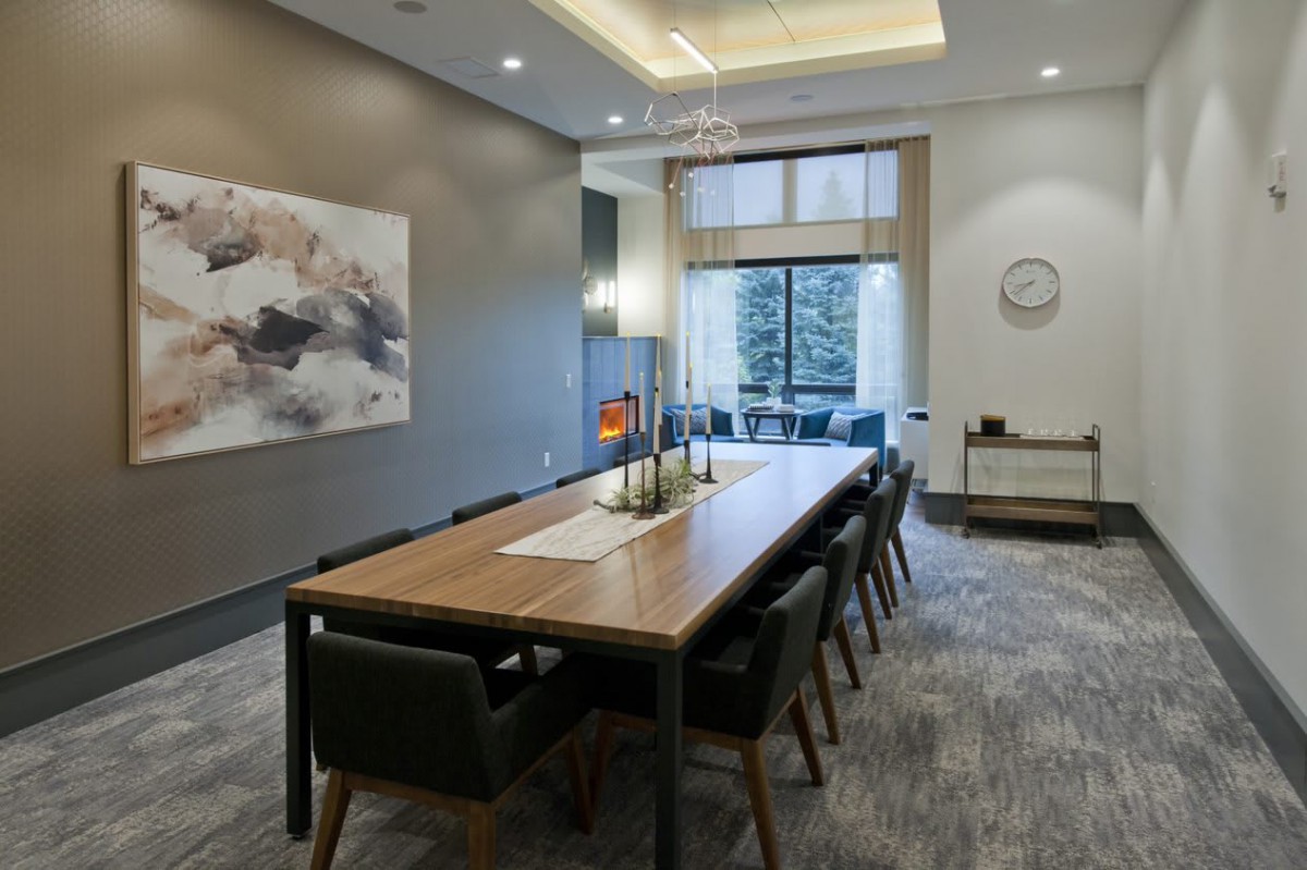 A modern conference room with a large wooden table, comfortable seating, and contemporary artwork on the wall.
