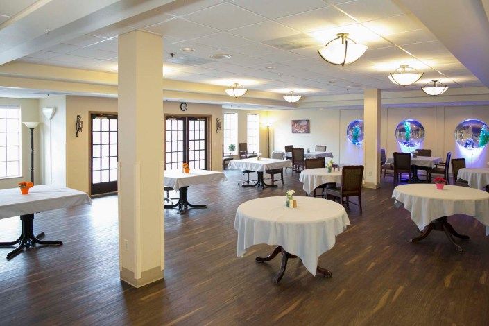 An empty restaurant dining area with round tables and chairs arranged neatly.