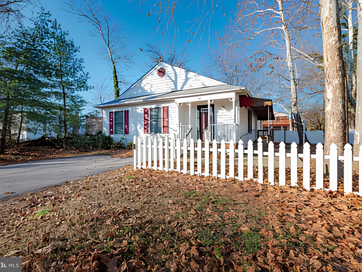 A charming house with a white picket fence surrounded by autumn leaves.
