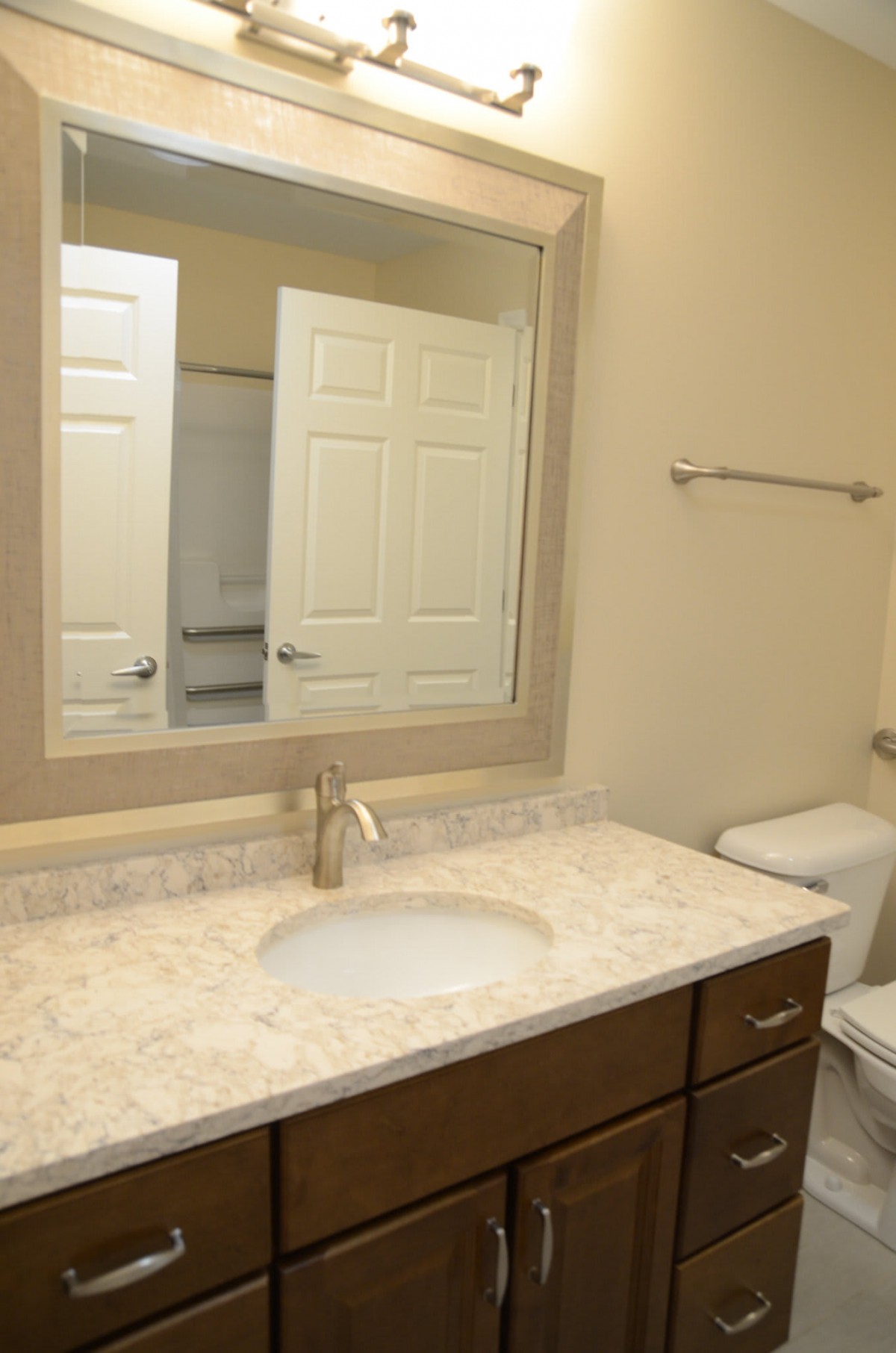 A clean and modern bathroom with a mirror, sink, and toilet.