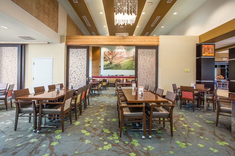 A modern dining area with neatly arranged tables and chairs, featuring stylish decor and a chandelier.
