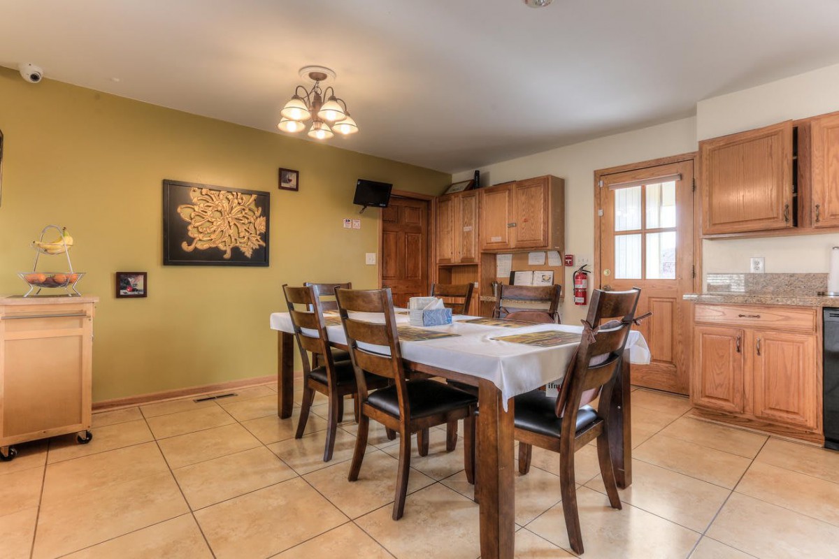 A cozy dining room with a wooden table and chairs, decorated with artwork and featuring a warm light fixture.