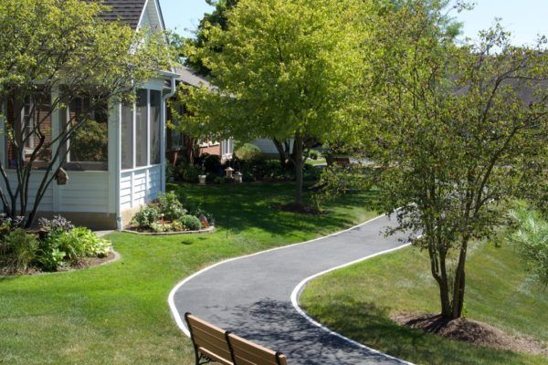 A peaceful garden pathway winding through a lush, landscaped yard next to a house.