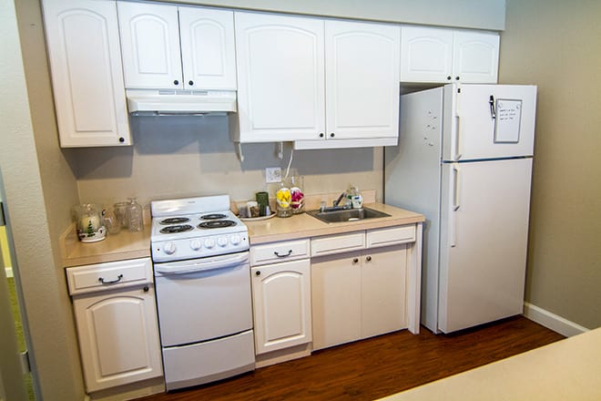 A kitchen with white cabinets, a stove, and a refrigerator.