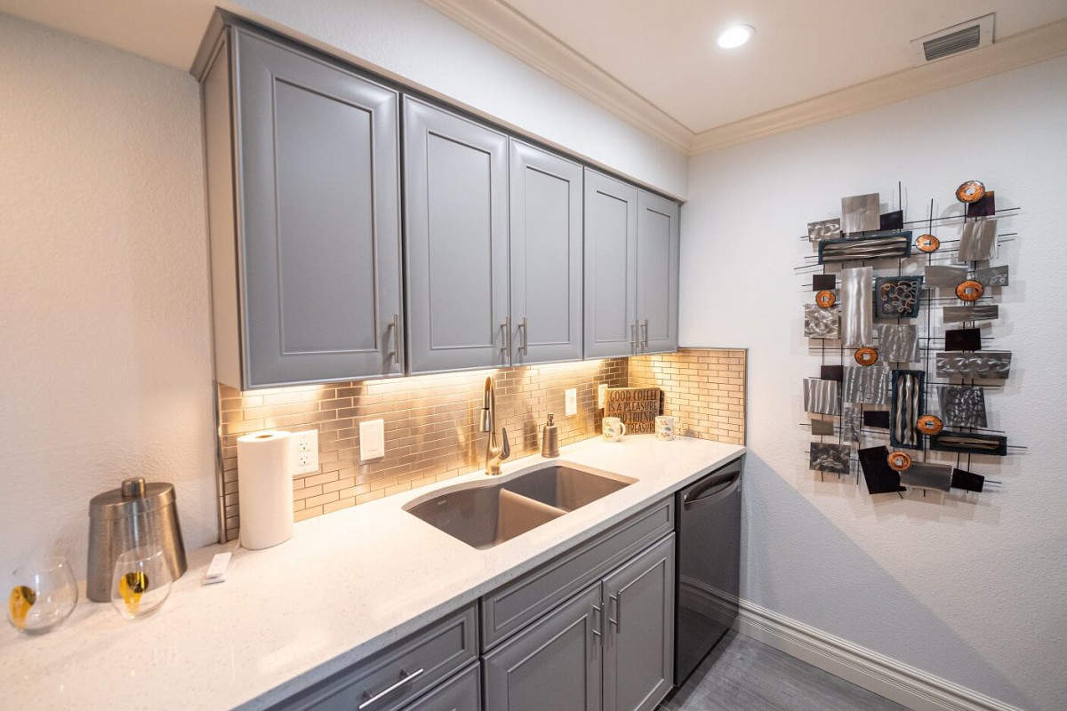 A modern kitchen with gray cabinets, a sleek countertop, and ambient lighting.