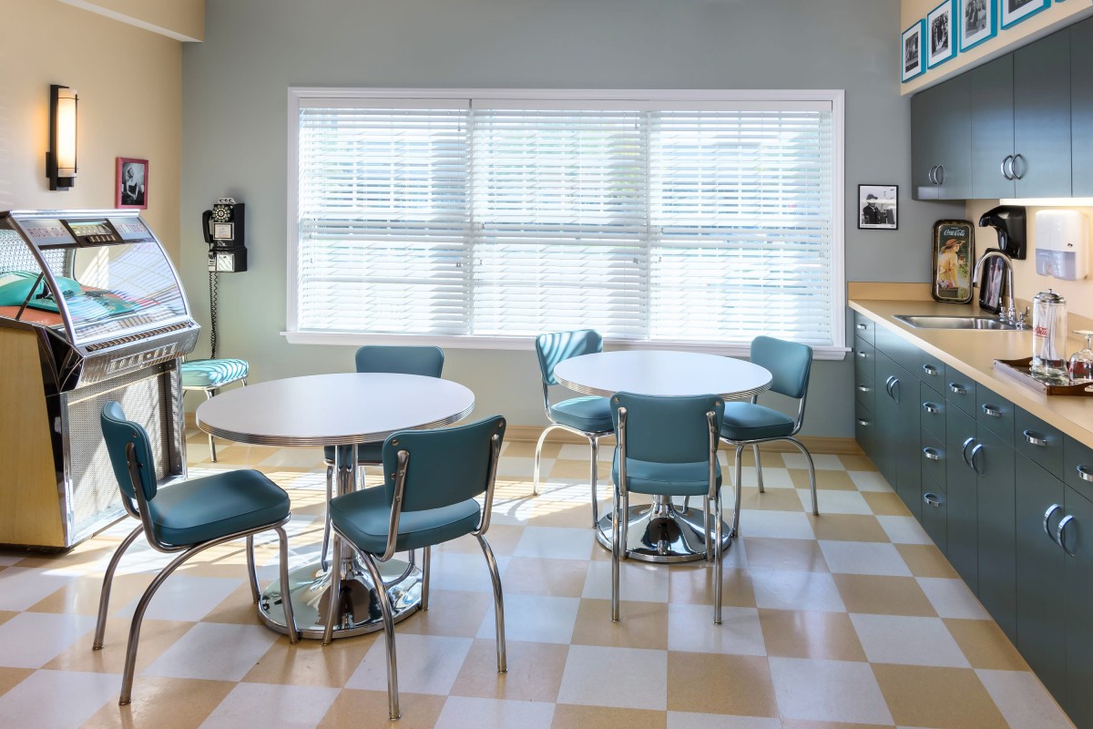 A retro-style diner interior with teal chairs and checkered flooring.